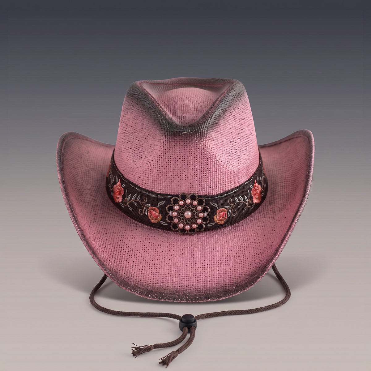 Chapeau de cowboy Rosalia en paille rose patinée, bandeau brodé de roses et cordon de maintien, vu de face